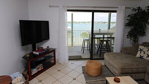 Una sala de estar con televisión, sofá y vista al agua.