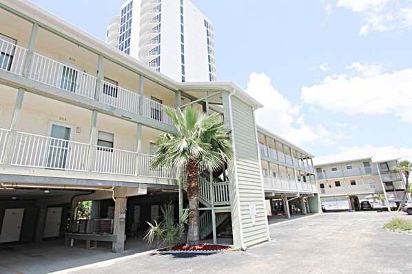 A multi-story hotel with balconies, a palm tree, and a parking area. - B.E.A.C.H.🏖️ Best escape anyone can have🌊 (Gulf Shores)