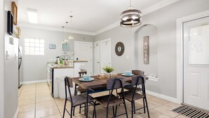 Une cuisine moderne dotée d’un îlot central, d’un coin repas avec une table et des chaises en bois, et d’un luminaire suspendu au-dessus.