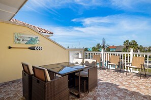 A patio with a table and chairs, a mural on the wall, and a tiled floor. - Chic Coastal Condo with Private Terrace • 1 Min Walk to Beach • Pool (South Padre Island)