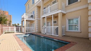 Un immeuble résidentiel doté d’une piscine, de balcons et d’un chemin en briques.