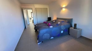A modern bedroom with a bed, a bedside table, and a nightstand. There is a door leading to another room. - Les Marronniers, Six-Fours-les-Plages / 10 min from the beach, 4-room, 78 m² (Six-Fours-les-Plages)