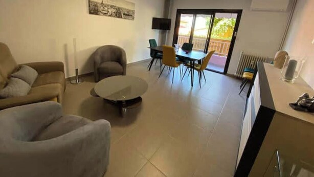 A living room with a sofa, armchair, and a coffee table. There is a dining area with a table and chairs. A painting is on the wall, and a radiator is on the floor. - Les Marronniers, Six-Fours-les-Plages / 10 min from the beach, 4-room, 78 m² (Six-Fours-les-Plages)
