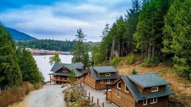 Een chalet met houten gevel, een veranda en uitzicht op een meer en bos.