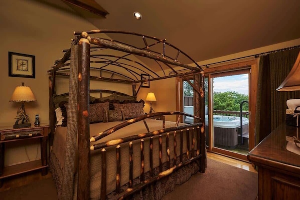 A four-poster bed with a rustic design, a hot tub visible through the glass door, and a framed picture on the wall.