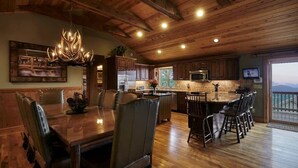 Une cuisine spacieuse avec des meubles en bois, un grand îlot central et un coin repas agrémenté d’un lustre.