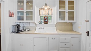 A kitchen with white cabinets, a sink, and a window with a rooster decoration. - Deannies Cottage 2 Bedroom Cottage by RedAwning (Fredericksburg)
