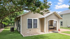 A single-story house with a front porch, a small attached garage, and a well-maintained lawn. - Deannies Cottage 2 Bedroom Cottage by RedAwning (Fredericksburg)