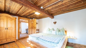 A bedroom with a wooden ceiling, a bed with green and white bedding, a wooden wardrobe, and a heart-shaped decoration on the wall. - Quaint, rustic vacation home with hut flair on the sunny side of the Grimming (Mitterberg-St.Martin)
