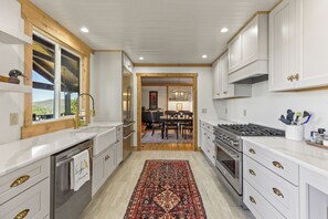 A modern kitchen with white cabinetry, stainless steel appliances, and a wooden ceiling.