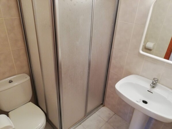 A bathroom with a toilet, a shower enclosure, and a sink.