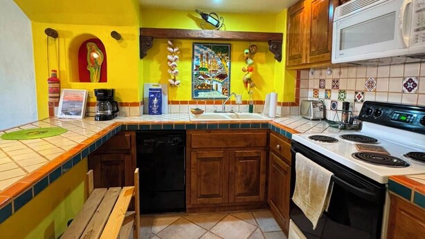 A kitchen with wooden cabinets, a microwave, a stove, and a sink. - Brisa del Mar – Pool, Near Mirador Beach (Puerto Penasco)