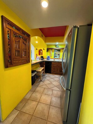 A compact kitchen with a refrigerator, a sink, and a wooden cabinet.