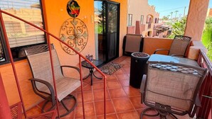 A covered outdoor area with a patio table and chairs, a decorative wall, and a view of the surrounding buildings. - Brisa del Mar – Pool, Near Mirador Beach (Puerto Penasco)
