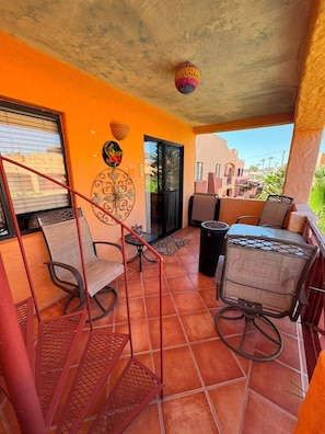 Un'area esterna coperta con tavolo e sedie da patio, un muro decorativo e vista sugli edifici circostanti.