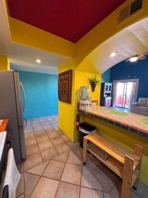 A kitchen with a refrigerator, a water dispenser, a bench, and a window with a view.