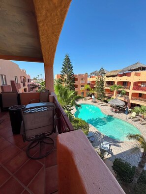 A balcony with a view of a swimming pool and resort buildings.