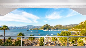 Vista costera con playa, barcos y montañas.