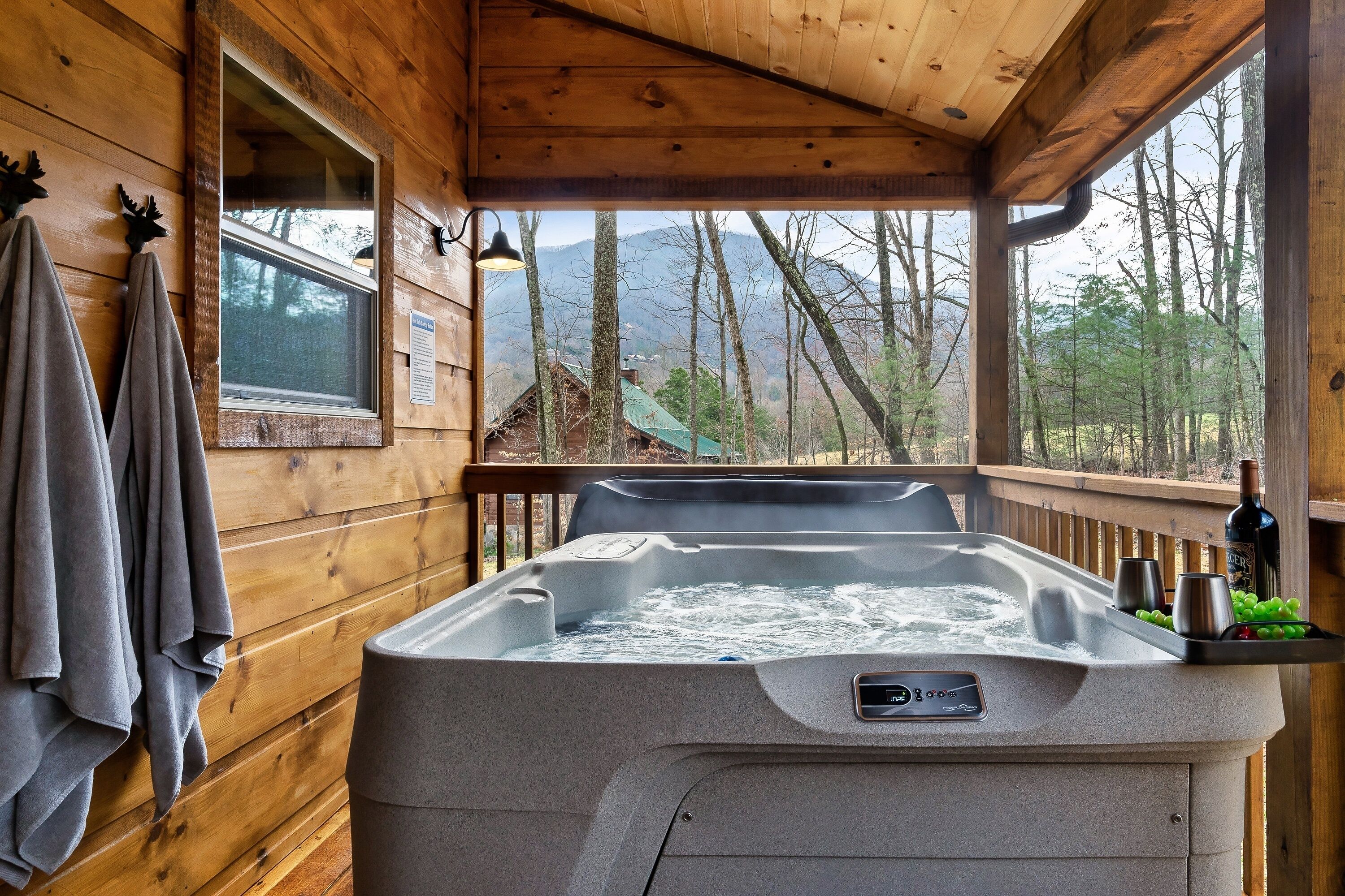 Una cabaña de madera con jacuzzi, toallas y vistas a montañas.