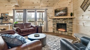 Ein gemütliches Wohnzimmer mit Kamin, Ledersofas und einer Wand aus Naturstein.