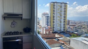 Eine Küche mit Gasherd und einem Fenster mit Blick auf eine Skyline mit hohen Gebäuden.