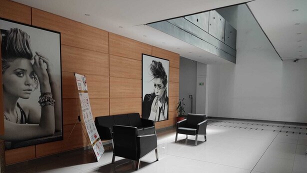 Eine moderne Lobby mit einer Rezeption, zwei schwarzen Sesseln und großformatiger Kunst am Wand.