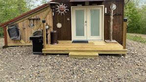 Un rustico chalet in legno con veranda, barbecue e decorazioni a forma di sole.