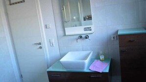 Un baño con un lavamanos blanco, un espejo y un armario.