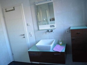 Un baño con un lavamanos blanco, un espejo y un armario.