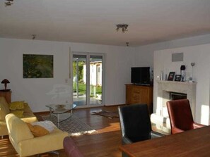 A living room with a sofa, a dining table, a TV, and a fireplace.