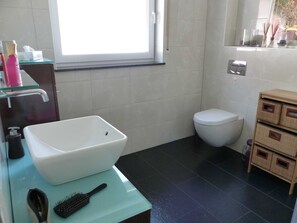 Un baño con lavamanos blanco, inodoro y espejo.