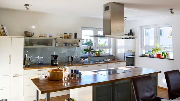 A modern kitchen with white cabinets, a wooden countertop, and a built-in oven.