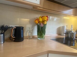 A kitchen counter with a coffee maker, a glass vase with flowers, and a pot on the stove. - Studio Apartment in Souterrain in Freiburg - Gasthaus Privatzimmer in Freiburg im Breisgau (Freiburg im Breisgau)