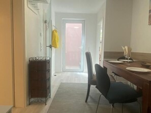 Un coin repas avec une table dressée pour deux personnes, une chaise et un petit meuble.