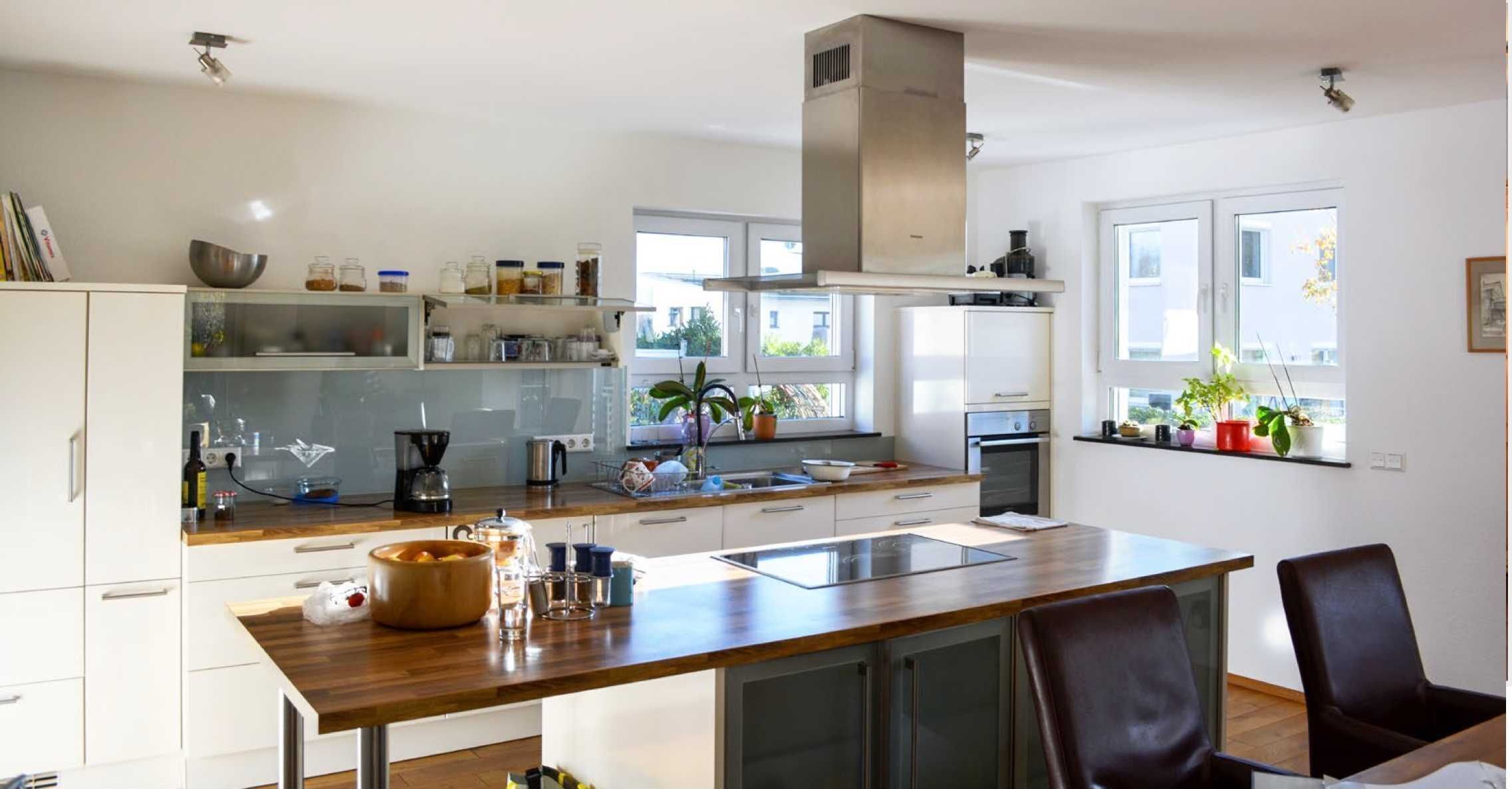 Eine moderne Küche mit weißen Schränken, einer Holz Arbeitsplatte und einem eingebauten Backofen.