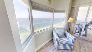 A room with a view of the ocean through large windows, a striped sofa, and a lamp.