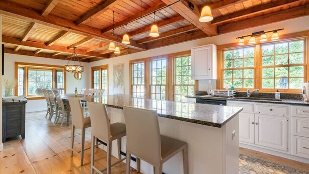 A spacious kitchen with a large island, wooden ceiling beams, and large windows. - Spacious Getaway with Sauna, Close to Newport & Beaches (Middletown)