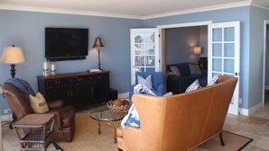 Una sala de estar con un sofá marrón, un televisor y un comedor con mesa y sillas.