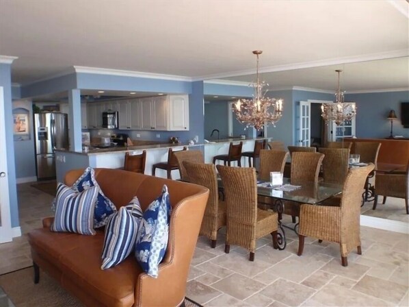 Relax in this stylish living area with a modern kitchen, featuring a leather sofa, dining table, and chandelier.