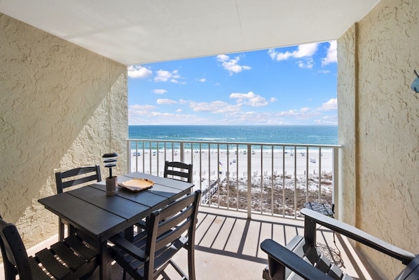 A balcony with a view of the beach and ocean.