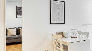 A modern, minimalist room with a white table, two chairs, a framed artwork, and a sofa in the background. - Bonjardim Studio Balcony by DA'HOME (Porto)