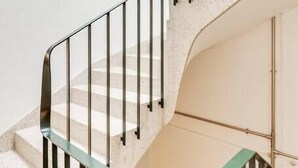 A spiral staircase with metal railings and a beige wall. - Bonjardim Studio Balcony by DA'HOME (Porto)
