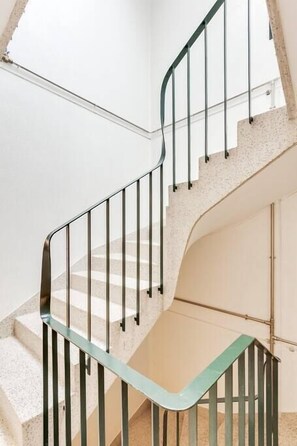 A spiral staircase with metal railings and a beige wall. - Bonjardim Studio Balcony by DA'HOME (Porto)