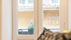 A room with a large window, a door with a small balcony, and a view of a building with a sign that reads "Punto Regga". - Bonjardim Studio Balcony by DA'HOME (Porto)
