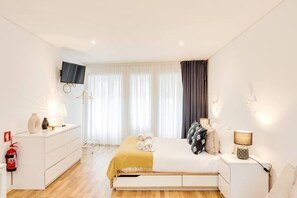 A modern bedroom with a bed, bedside tables, a TV, and a fire extinguisher. - Bonjardim Studio Balcony by DA'HOME (Porto)
