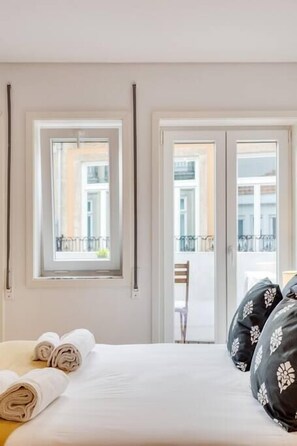 Une chambre d’hôtel avec un lit, des serviettes pliées et une vue sur le balcon extérieur.