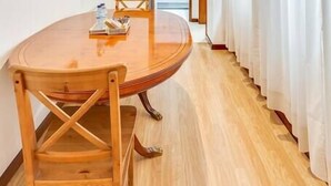 A room with a wooden dining table and chairs, a framed picture on the wall, and a door leading to another room.