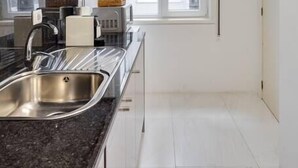 A modern kitchen with a stainless steel sink, a black countertop, and a window providing natural light.
