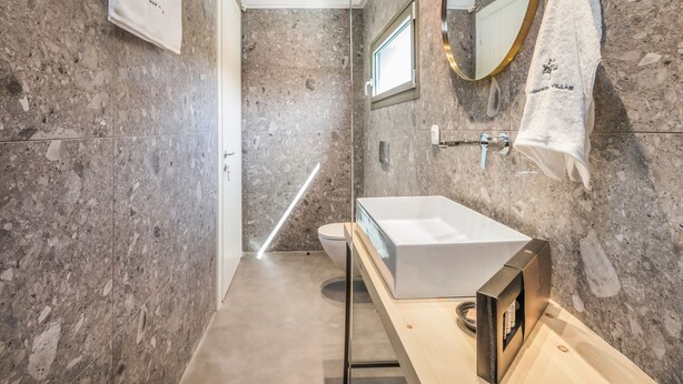 Een moderne badkamer met een marmeren wand, een witte wastafel en een handdoek aan de muur.