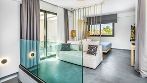 Una sala de estar moderna con un separador de vidrio, un sofá, una mesita y un columpio colgante.
